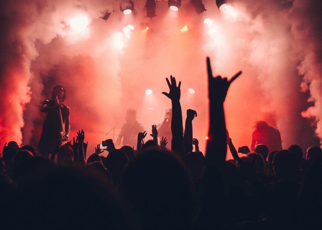 Dynamic scene of a rock band performing live with an enthusiastic audience and vibrant stage lights.